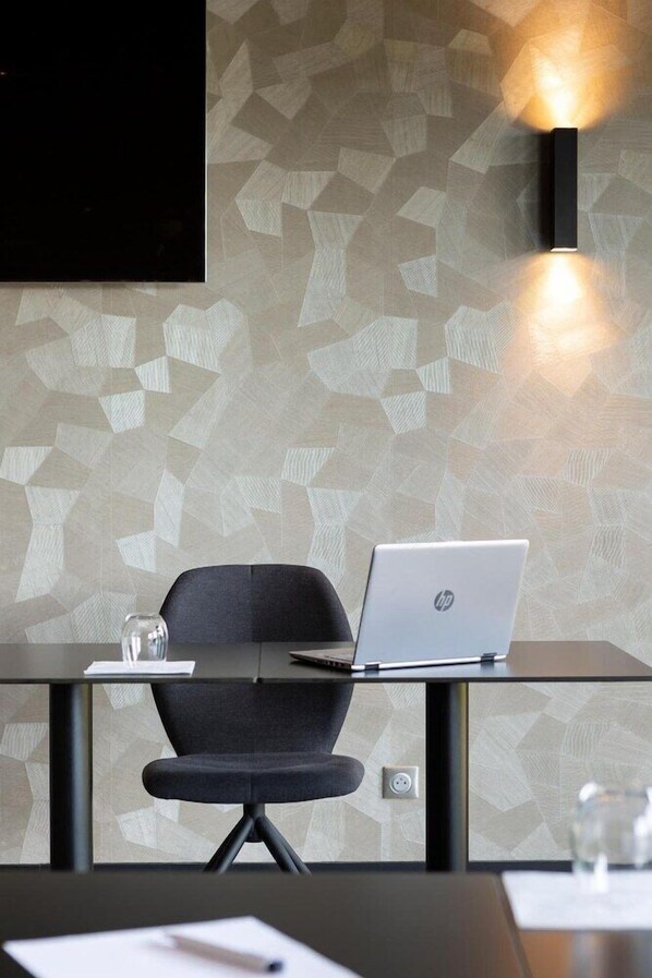 Un espace de bureau moderne avec un bureau en verre, une chaise noire et un ordinateur portable HP.
