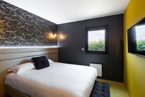 Um quarto moderno com uma cama grande, parede com padrão preto e branco, uma janela e uma TV de tela plana fixada na parede.