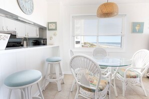 A kitchen with white cabinets, a stainless steel range hood, and a window overlooking the beach.