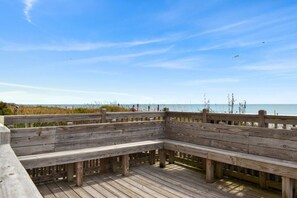 A wooden deck with benches overlooking a beach.