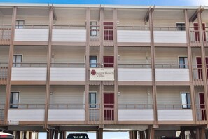A multi-story building with balconies, a sign indicating 'Crescent Beach Villas,' and a private label.