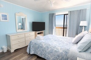 Un dormitorio con cama, cómoda, televisor y ventana con cortinas.