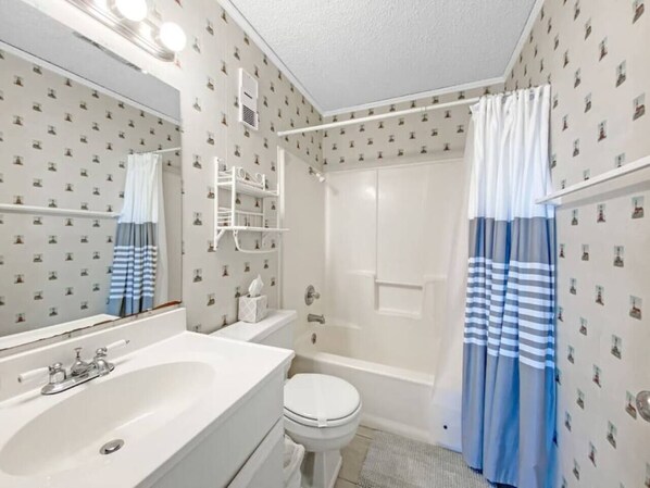Un baño con lavamanos blanco, inodoro y zona de ducha.
