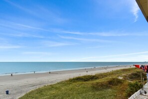 A beach with a clear sky, a sandy shore, and a few people.