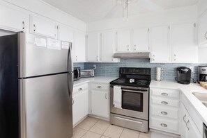 A modern kitchen with stainless steel appliances, white cabinetry, and a tiled backsplash.