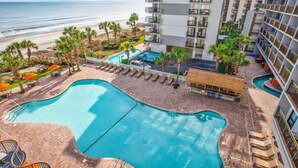 A hotel pool area with a view of the beach, palm trees, and a building with balconies. - Hot Tubs & Indoor Pools - First-Floor Privacy (Myrtle Beach)