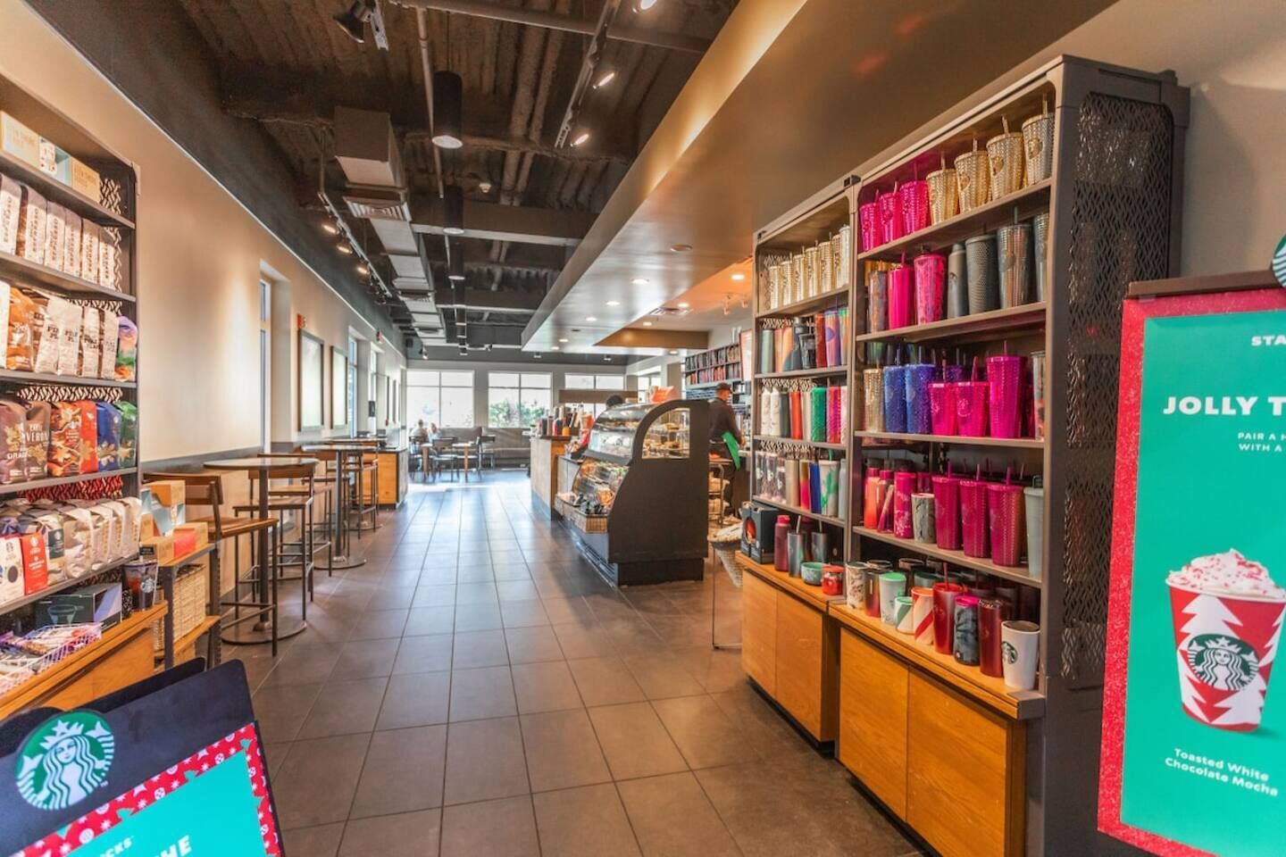 A Starbucks store interior with seating, a coffee machine, and shelves of merchandise.