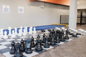 A large chessboard set up outdoors with two signs on the wall indicating no smoking and no running on the pool deck. - Hot Tubs & Indoor Pools - First-Floor Privacy (Myrtle Beach)