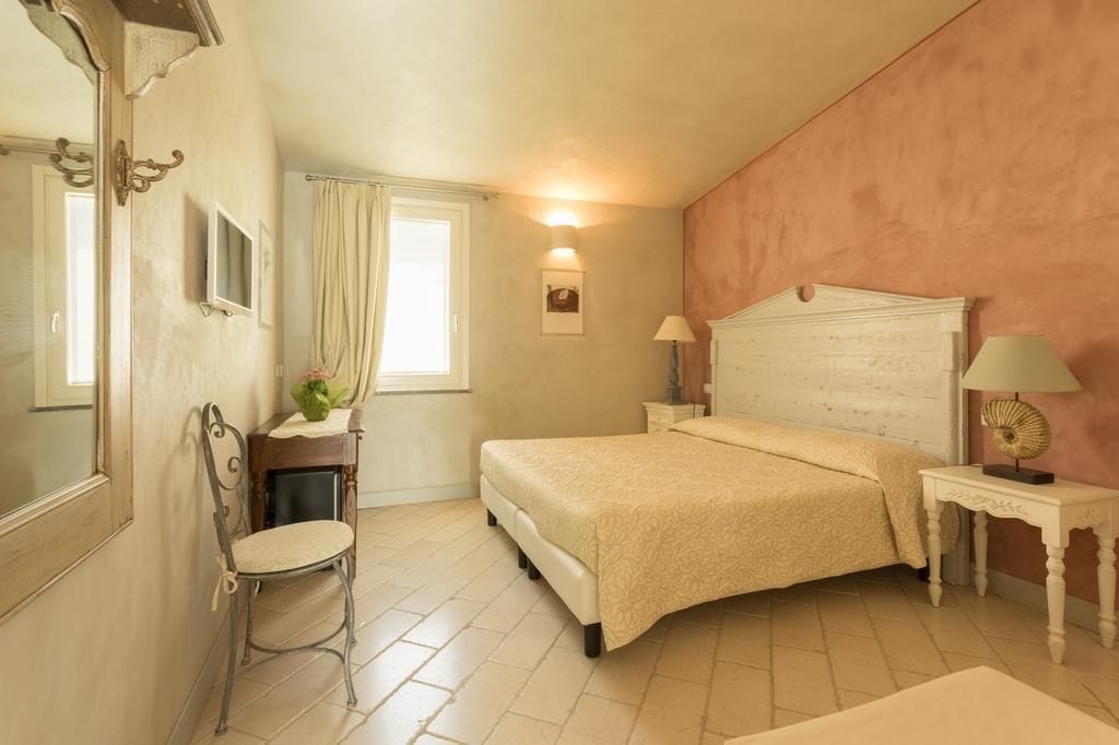 Un dormitorio con cama, una silla, un escritorio y un espejo.