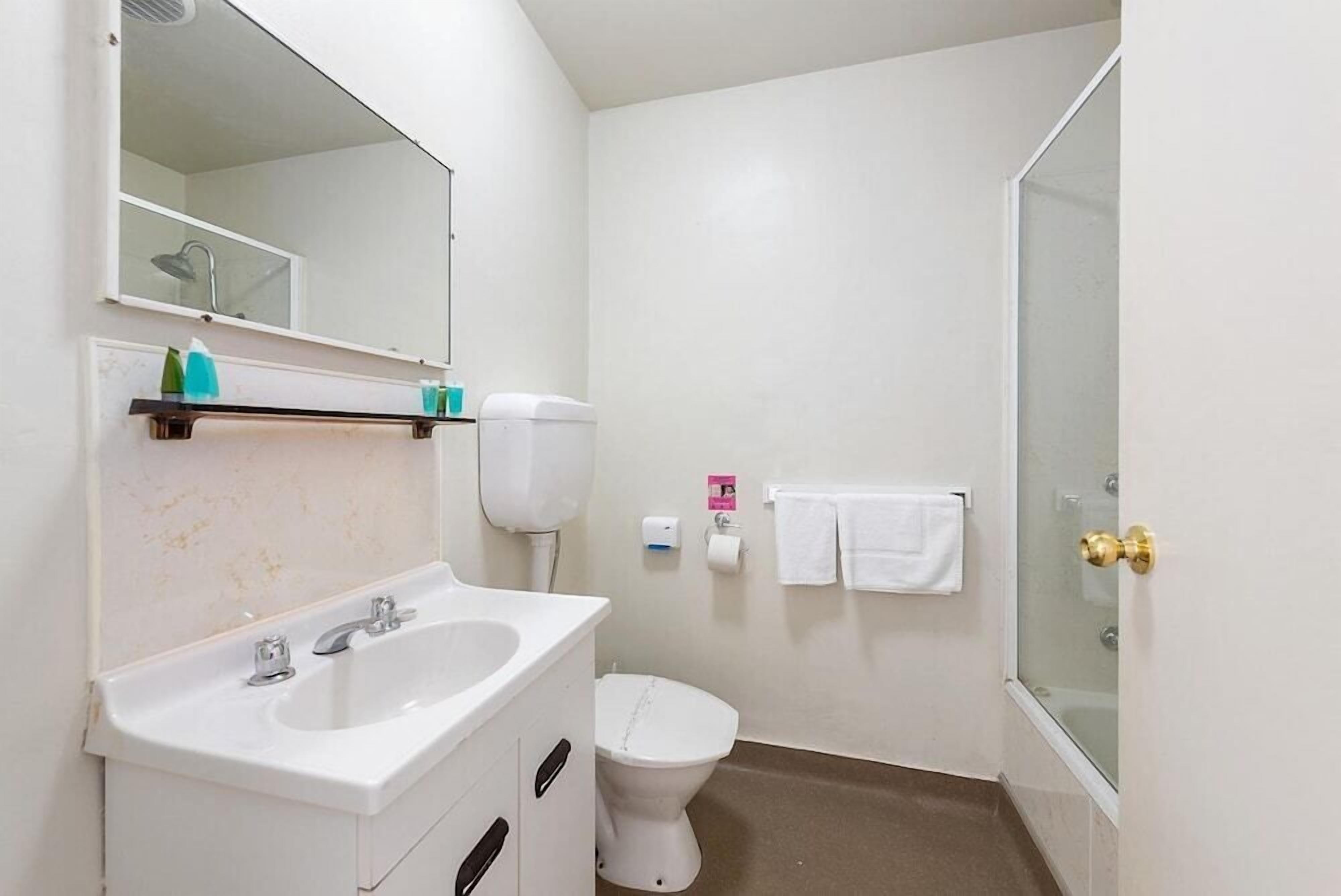 A small bathroom with a white sink, a toilet, and a shower.