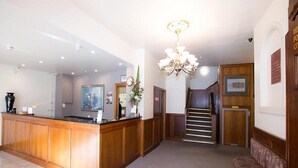 Un hall d’hôtel comprenant un comptoir d’accueil, un escalier et un espace détente.
