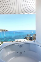 Una bañera grande y vacía con vista despejada al mar y la costa rocosa.