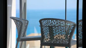 Un balcon avec des fauteuils en osier et une vue sur l’océan.