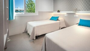Una habitació d'hotel amb dos llits individuals, una finestra amb vista a edificis i una paret amb un disseny decoratiu.
