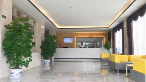 A modern reception area with a receptionist desk, seating area, and potted plants.