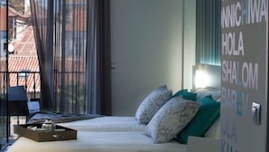 Een hotelkamer met een bed, kussens, een dienblad met spullen en een muur met tekst.