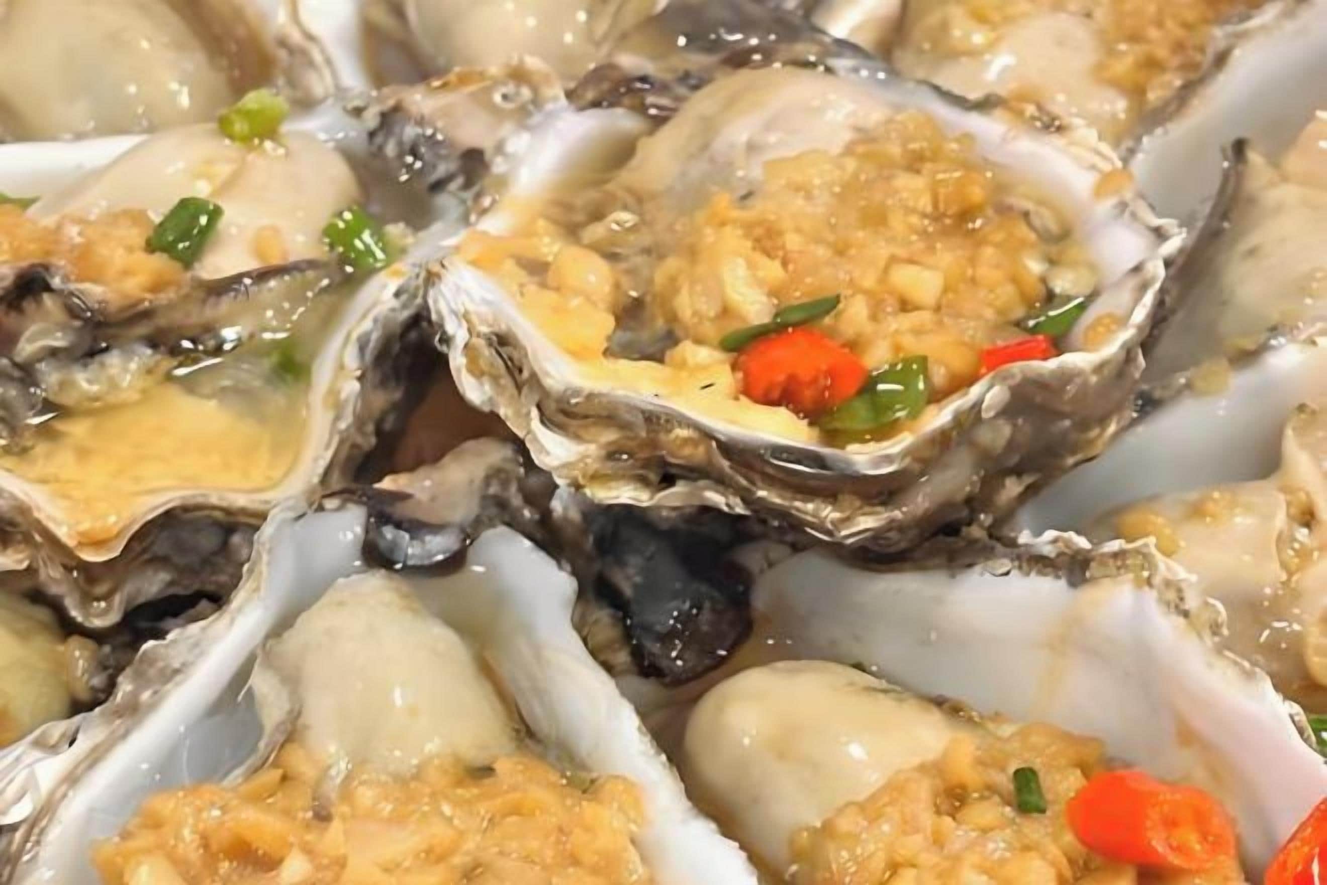A close-up of oysters with a topping, possibly a sauce or garnish.