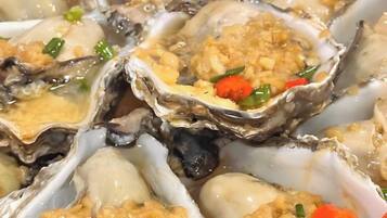 A close-up of oysters with a topping, possibly a sauce or garnish.