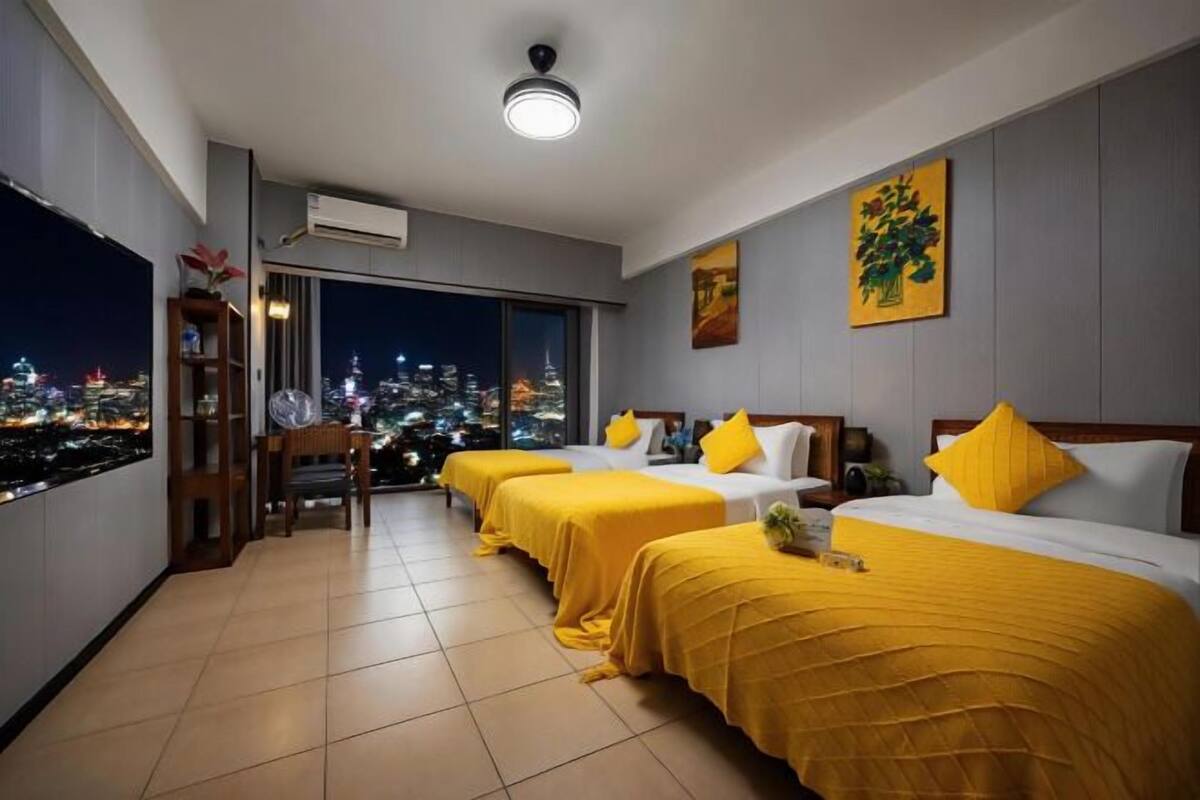 Een hotelkamer met twee bedden en uitzicht op een stadslandschap, met een groot raam.