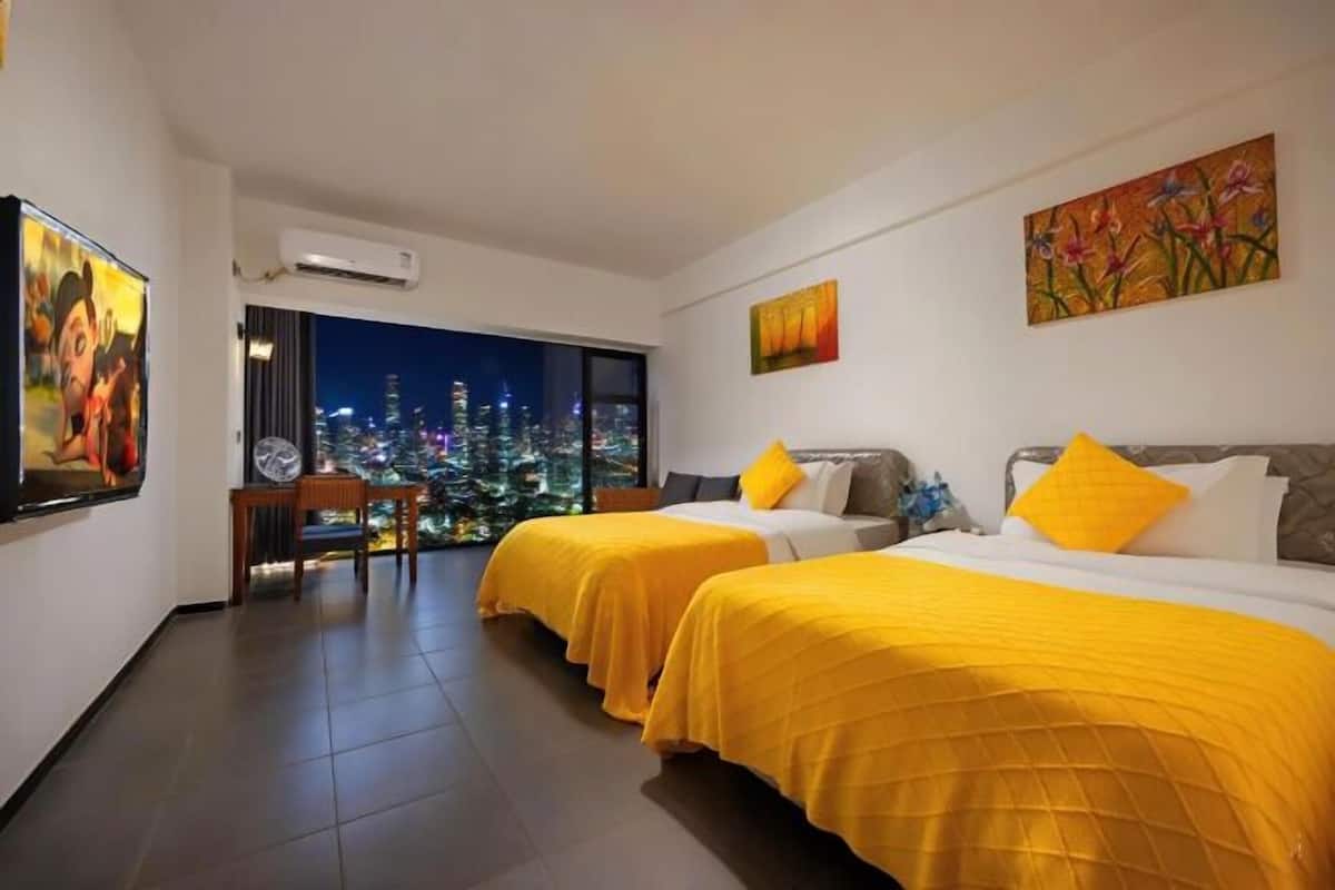 Een hotelkamer met twee bedden, stadszicht, een zithoek en kunstwerken aan de muren.