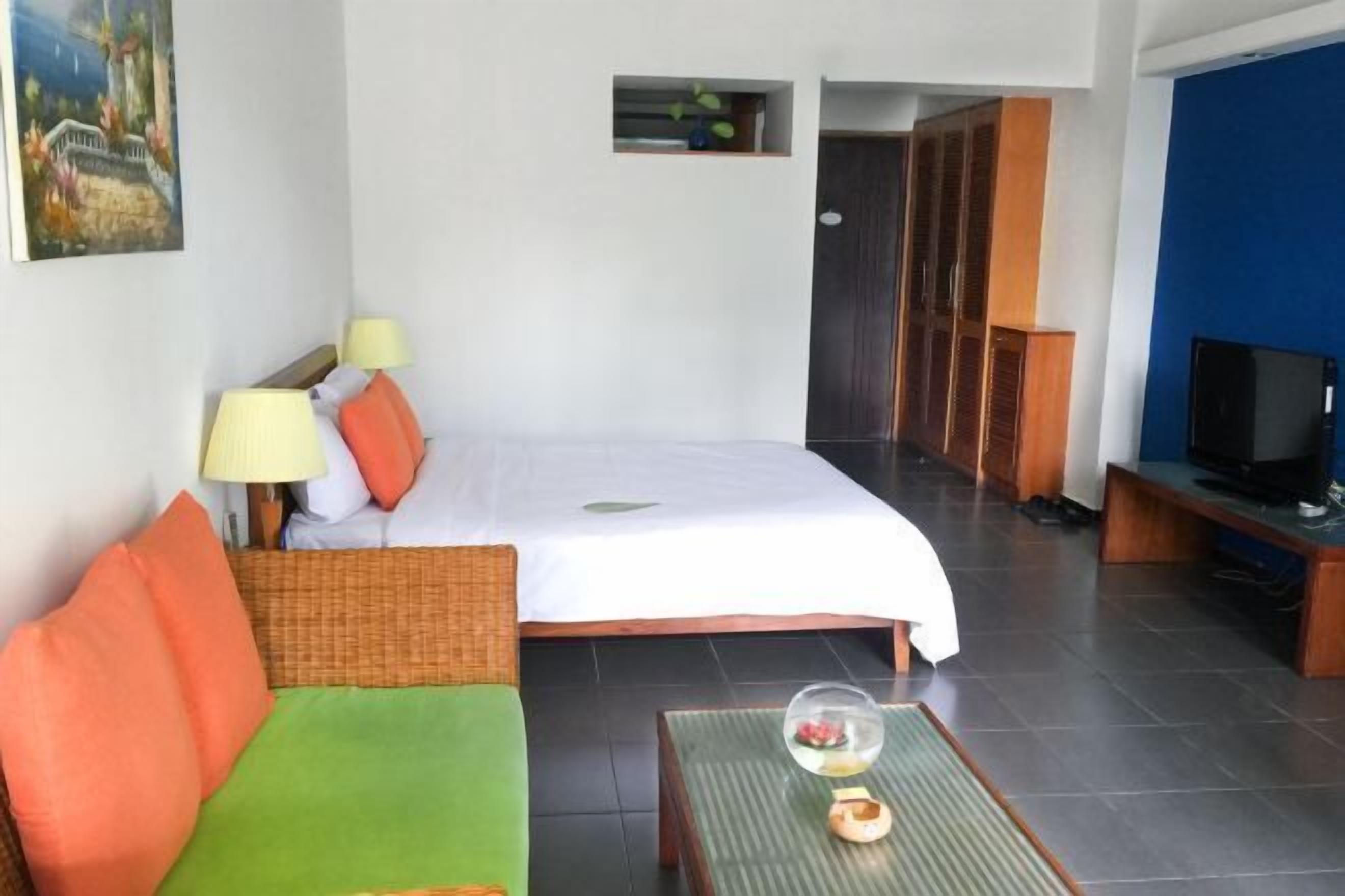 Habitación de hotel con cama, sofá, televisión y una mesita con un adorno.