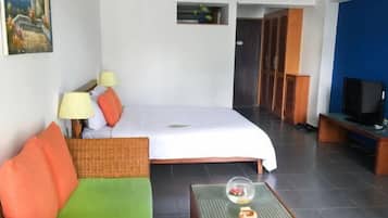 Habitación de hotel con cama, sofá, televisión y una mesita con un adorno.
