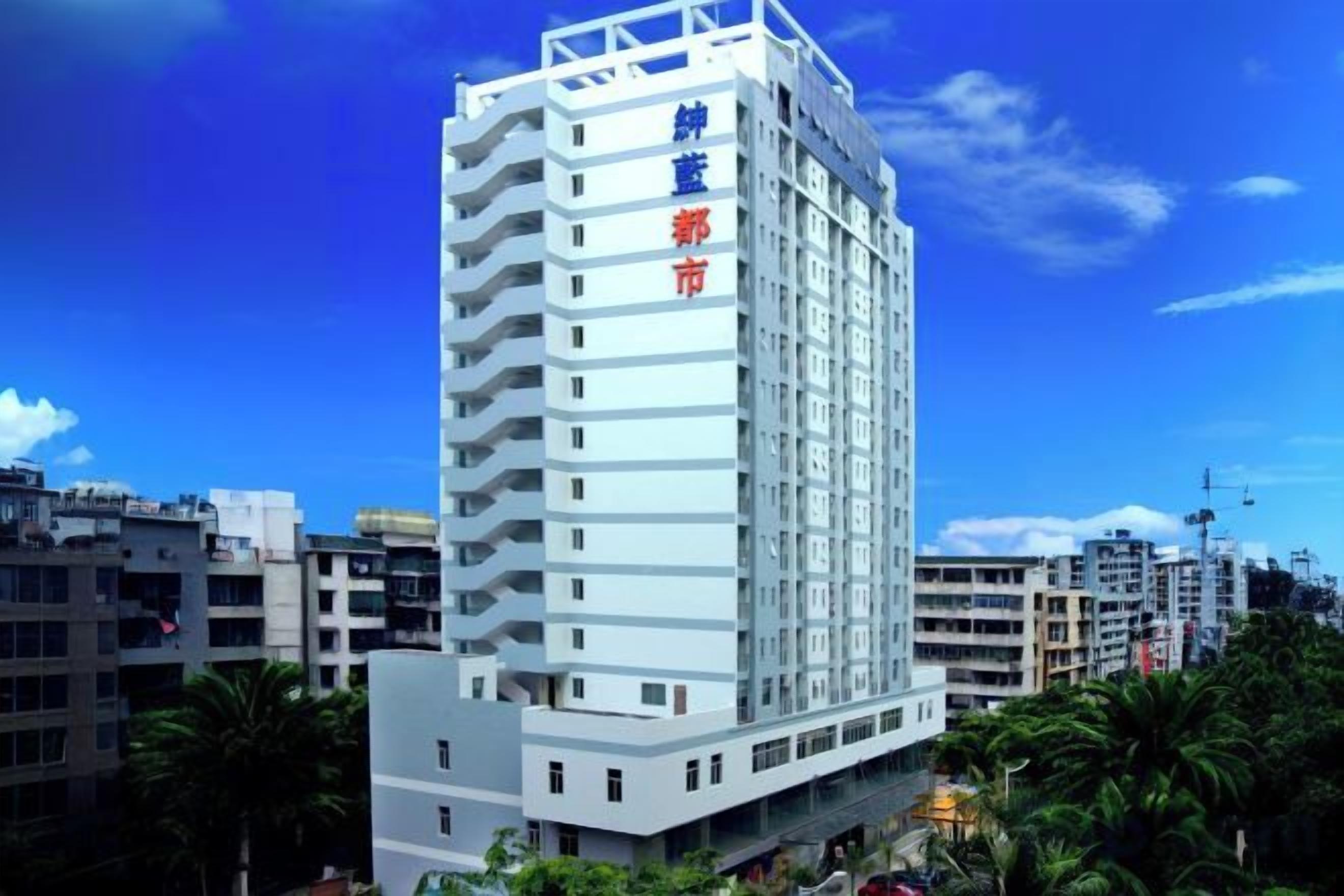 Un edificio de varios pisos con fachada blanca y señalización que indica que es un hotel.