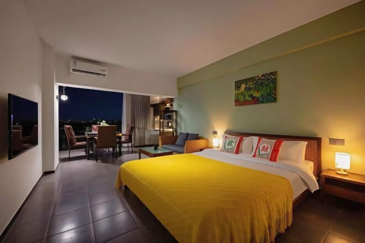 Een hotelkamer met een bed, een bureau, een stoel, een nachtkastje en een schilderij aan de muur.