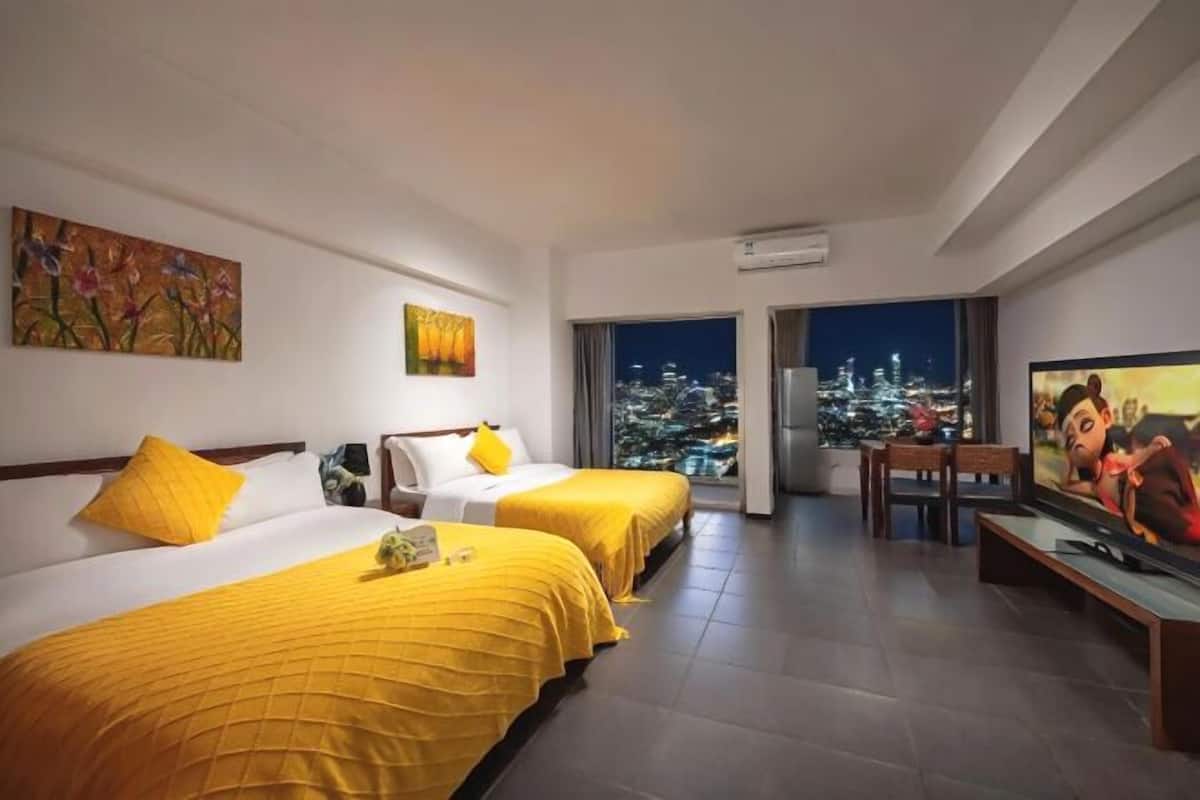 Een hotelkamer met twee bedden, een televisie en uitzicht over de stad.