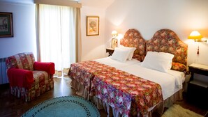 A bedroom with a large bed, two nightstands, a chair, and a window with curtains. - Casa Do Castelo (Peniche)