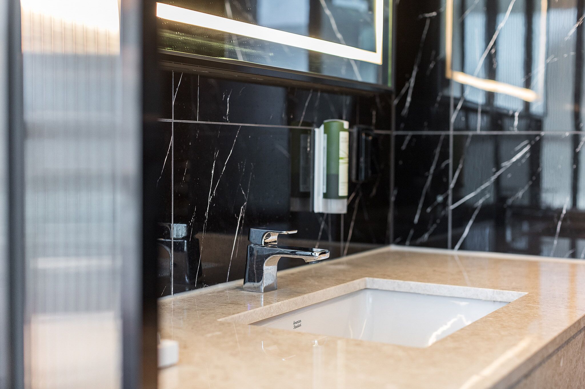 Un baño moderno con un espejo grande, un grifo cromado y un lavabo blanco.