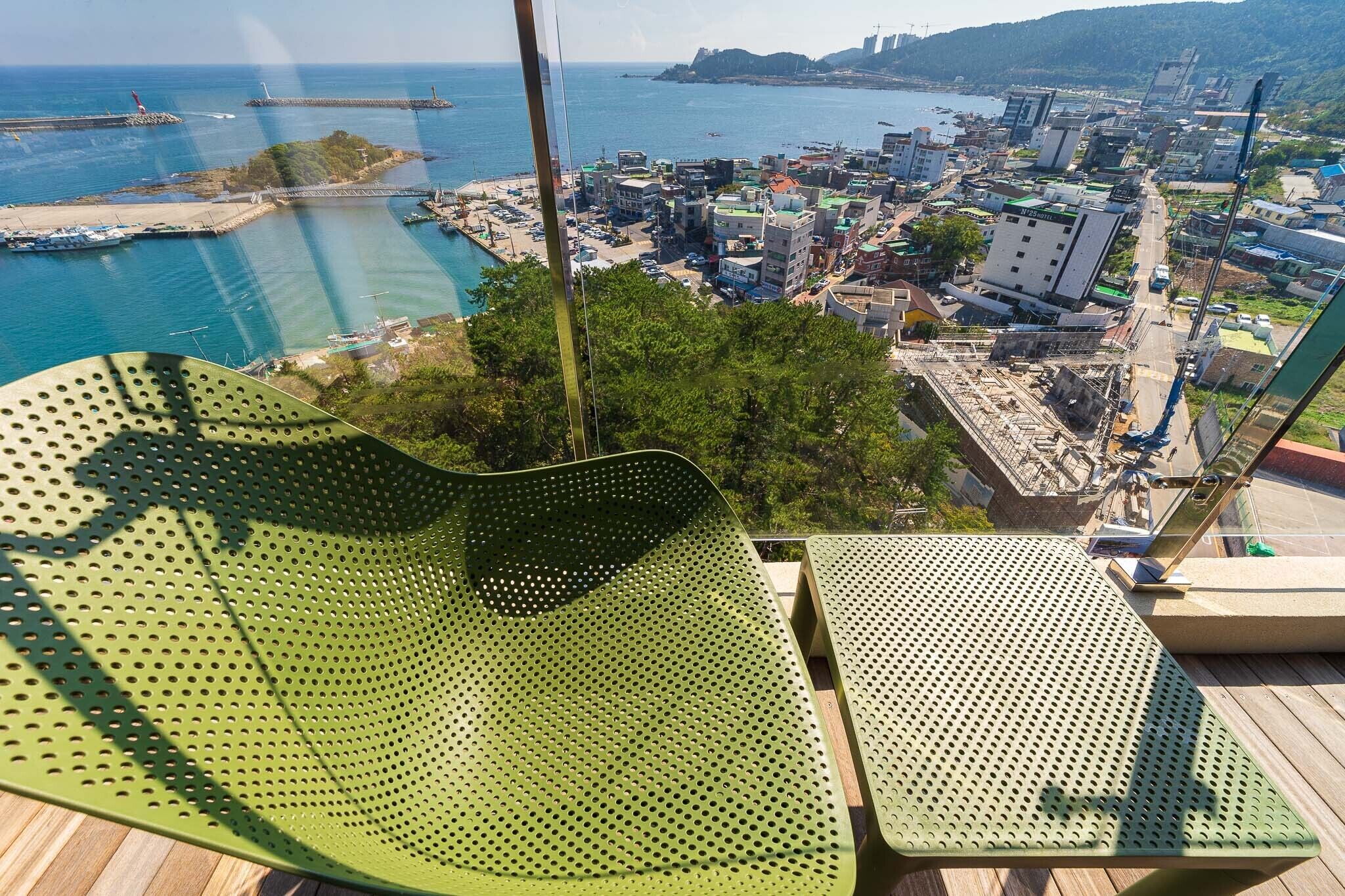 A high vantage point overlooking a coastal city with a view of the sea, buildings, and a clear sky.