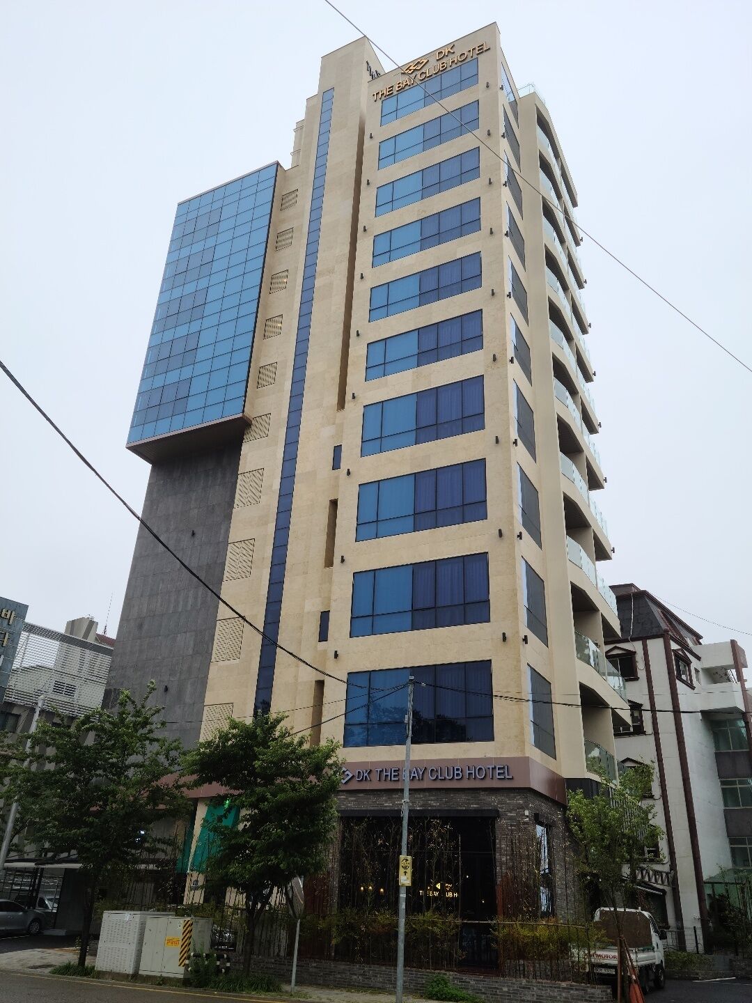 A multi-story hotel with a modern facade, featuring a prominent glass section on the left and a series of balconies on the upper floors.