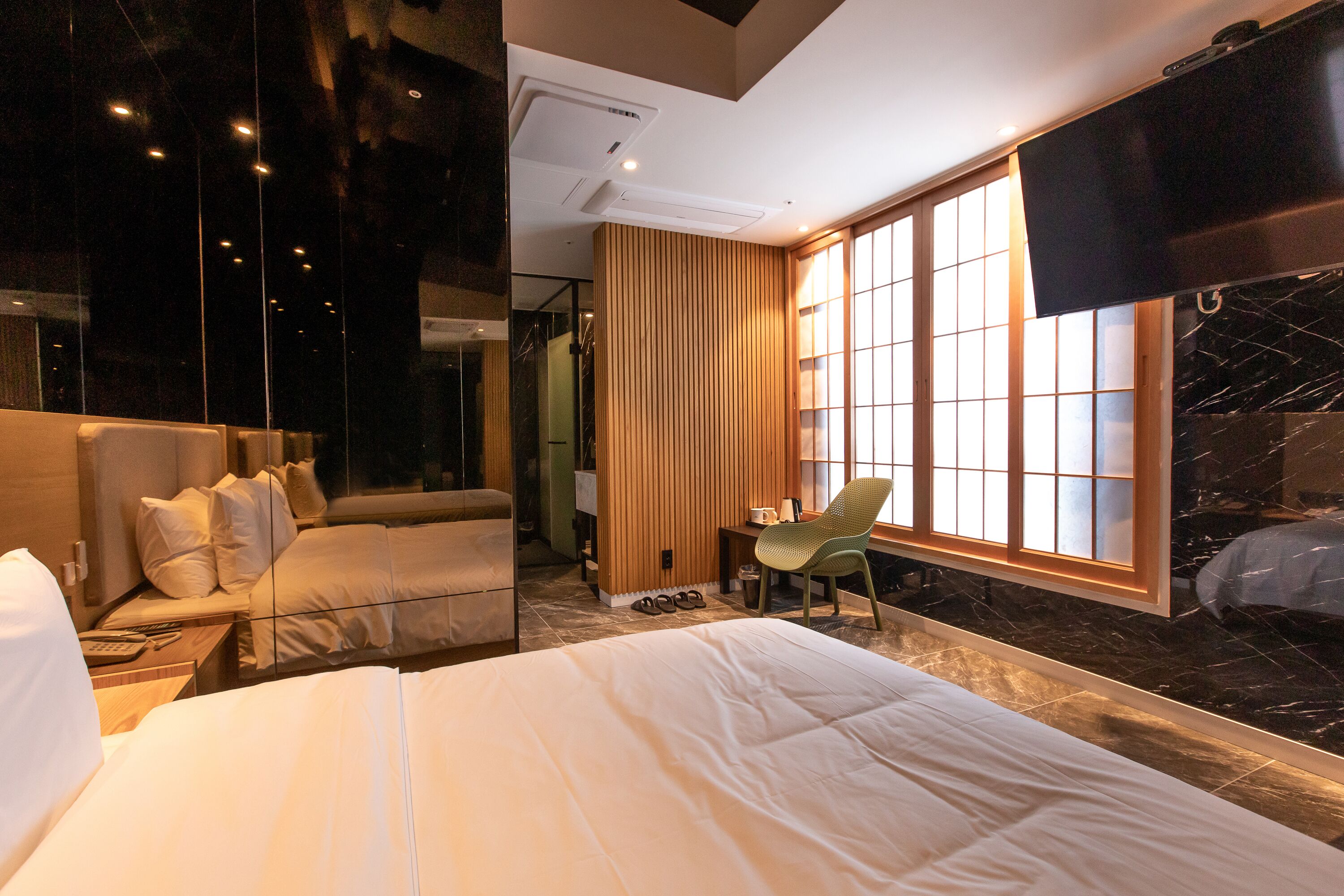 A hotel room with a large bed, a desk, a chair, and a TV.