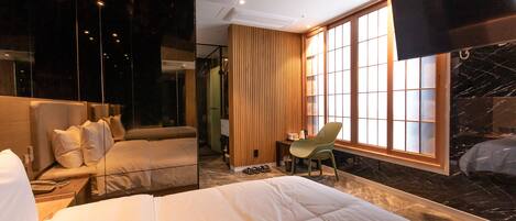A hotel room with a large bed, a desk, a chair, and a TV.