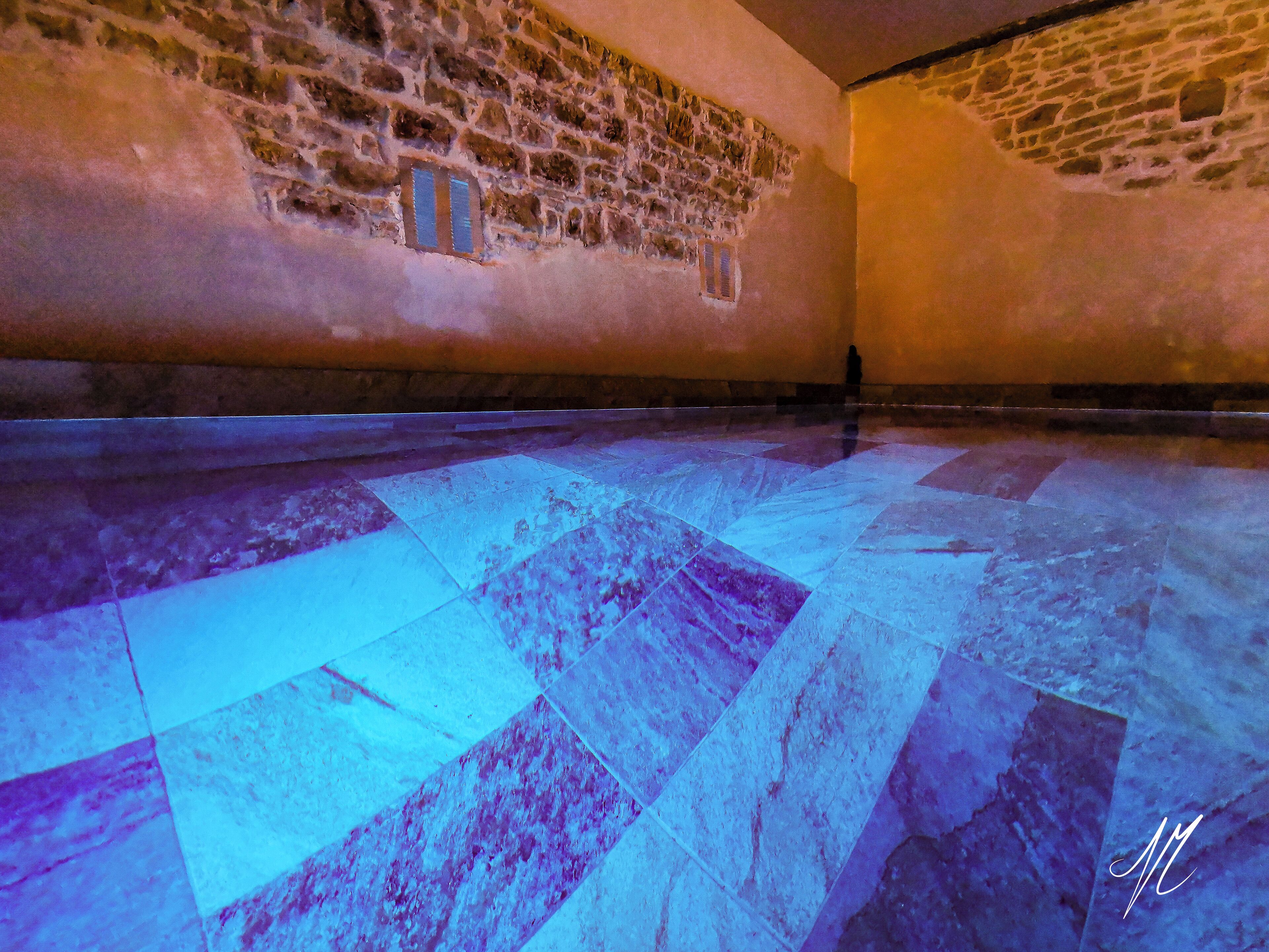 Quarto com parede de pedra e chão de azulejos.