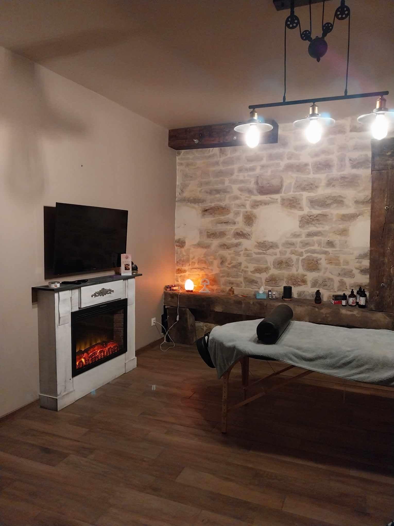 Een knus interieur met een stenen muur, een open haard, een televisie en een bed.