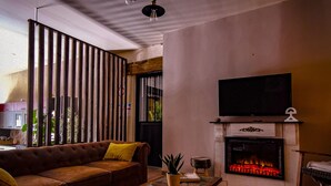 Een woonkamer met een bank, een salontafel, een open haard en een televisie.