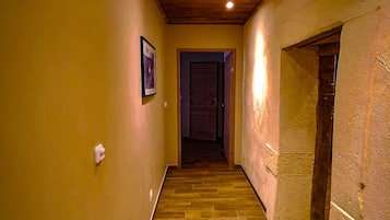 A narrow hallway with wooden flooring and a wooden ceiling.