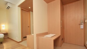 Una habitación de hotel con un armario de madera, una mesita de noche pequeña y una cama.