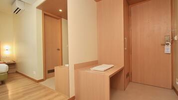 A hotel room with a wooden wardrobe, a small bedside table, and a bed.