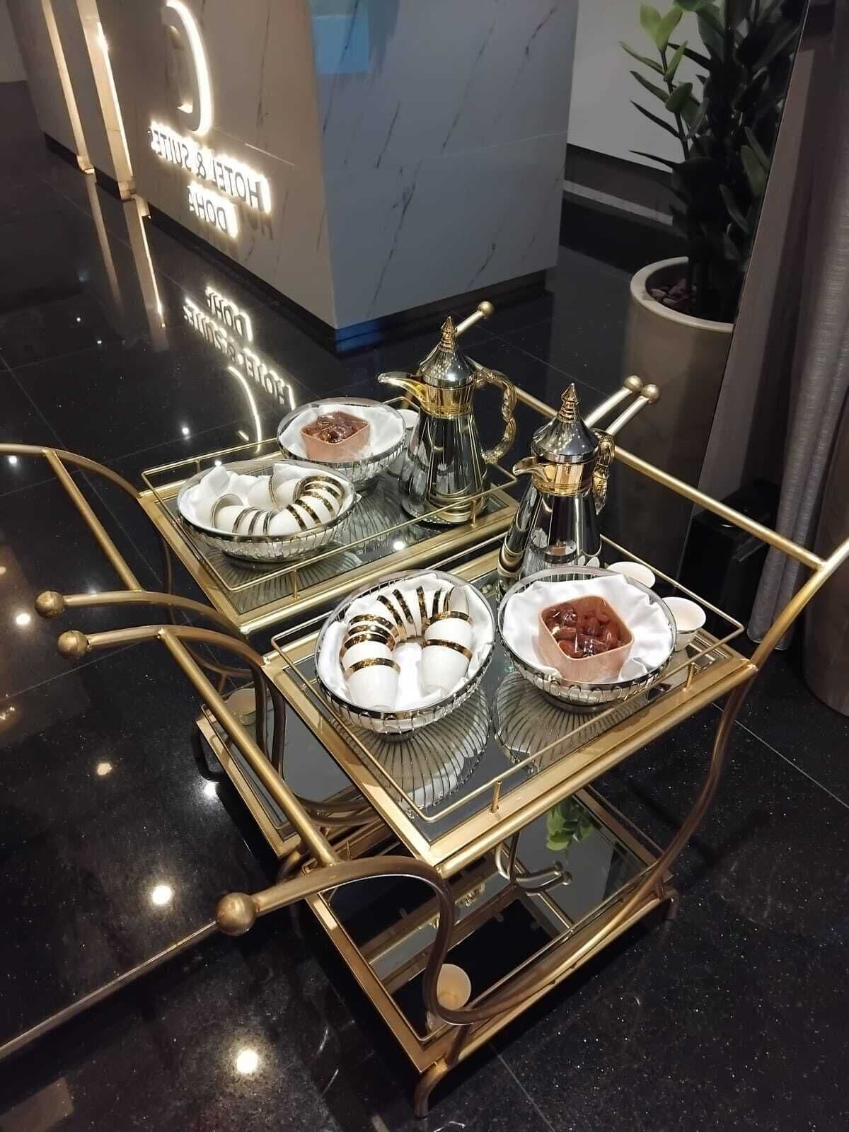 A luxurious hotel lobby with a modern reception desk and a decorative cart with fine china and silverware.