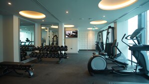 Un gimnasio con equipo de ejercicio, bancos y una pantalla de televisión.
