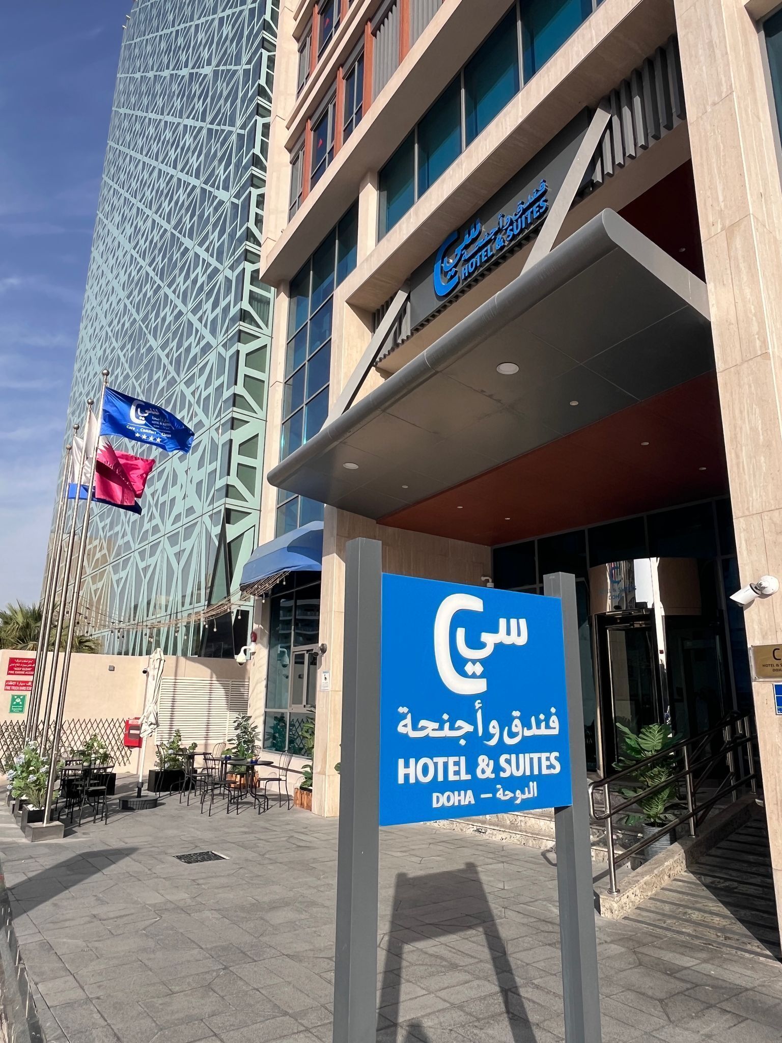 Entrada de un hotel con un cartel que indica que es un hotel y suites en Doha.