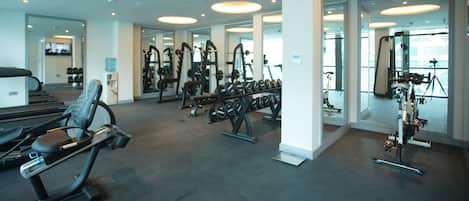 Uma academia moderna com aparelhos de cardio, equipamentos de musculação e espelhos.