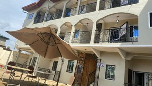 Un edificio de varios pisos con balcones, una zona de estar al aire libre cubierta y una escalera.