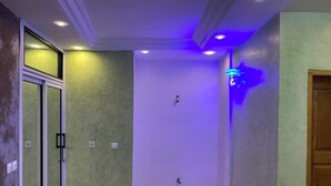 Un pasillo con una puerta de cristal a la izquierda, una pared iluminada en azul a la derecha y una puerta sencilla al final.