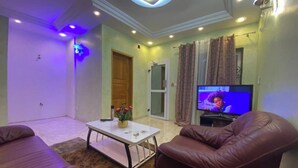 Una sala de estar con televisor, sillones de cuero, una mesa de centro y una puerta.