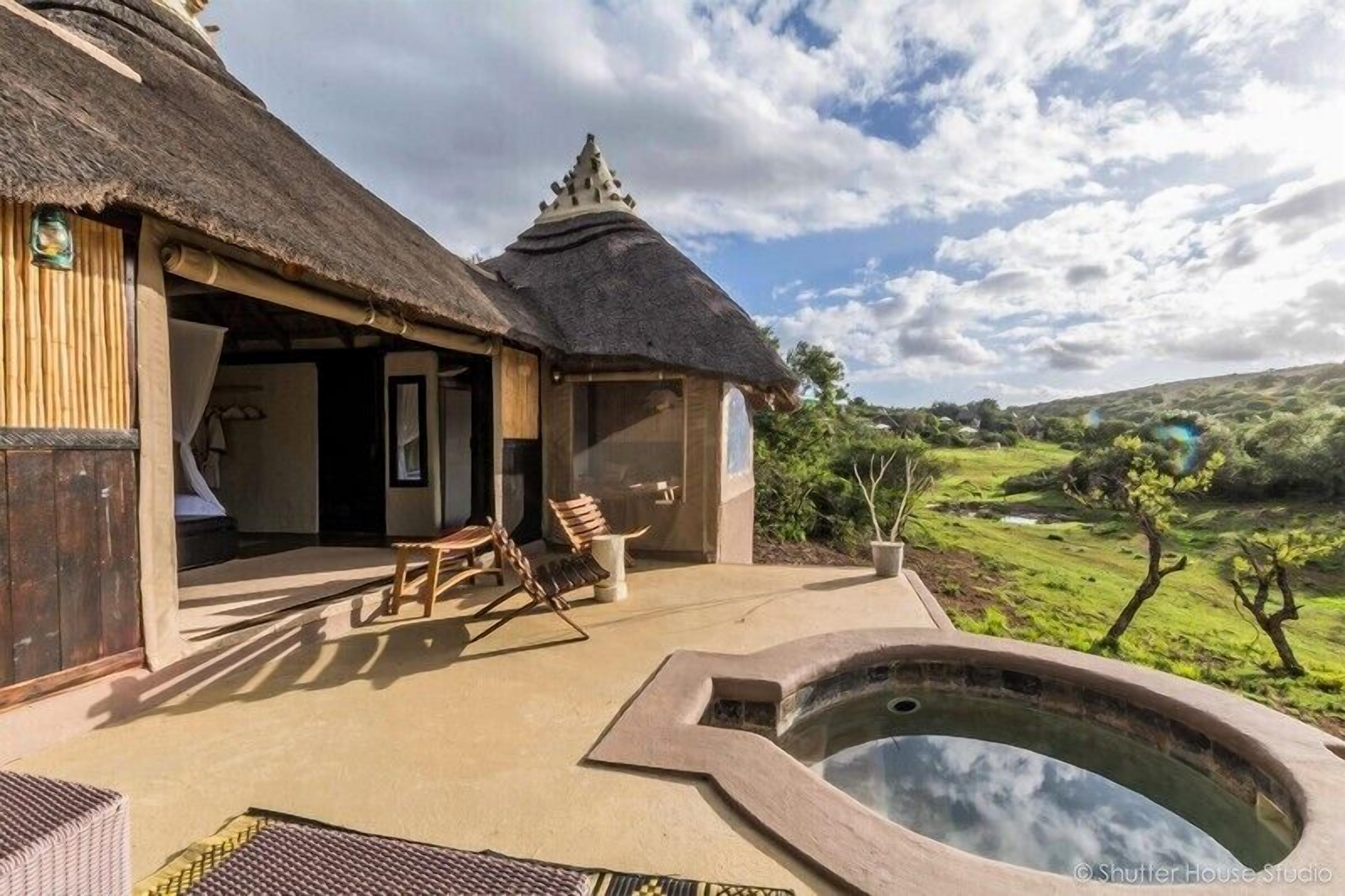 A thatched-roof building with a pool and outdoor seating.