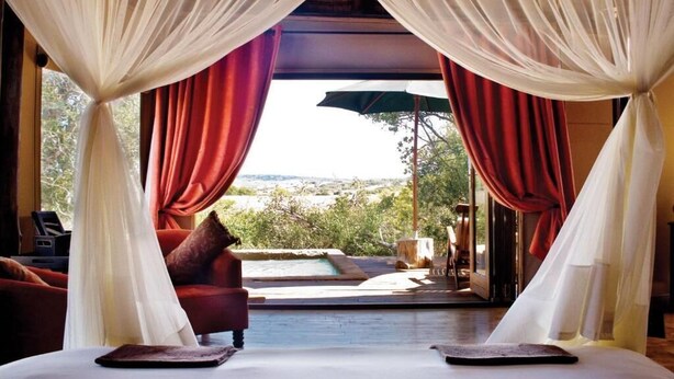 Quarto com vista para uma piscina e paisagem.